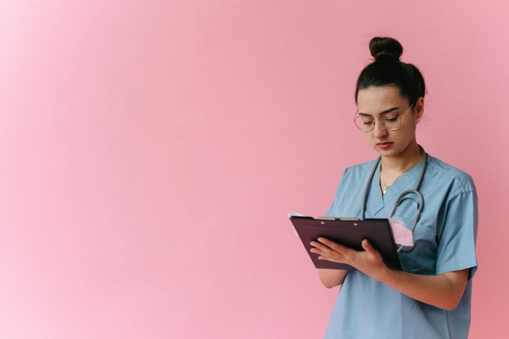 A young nurse in scrubs, looking at medical charts.