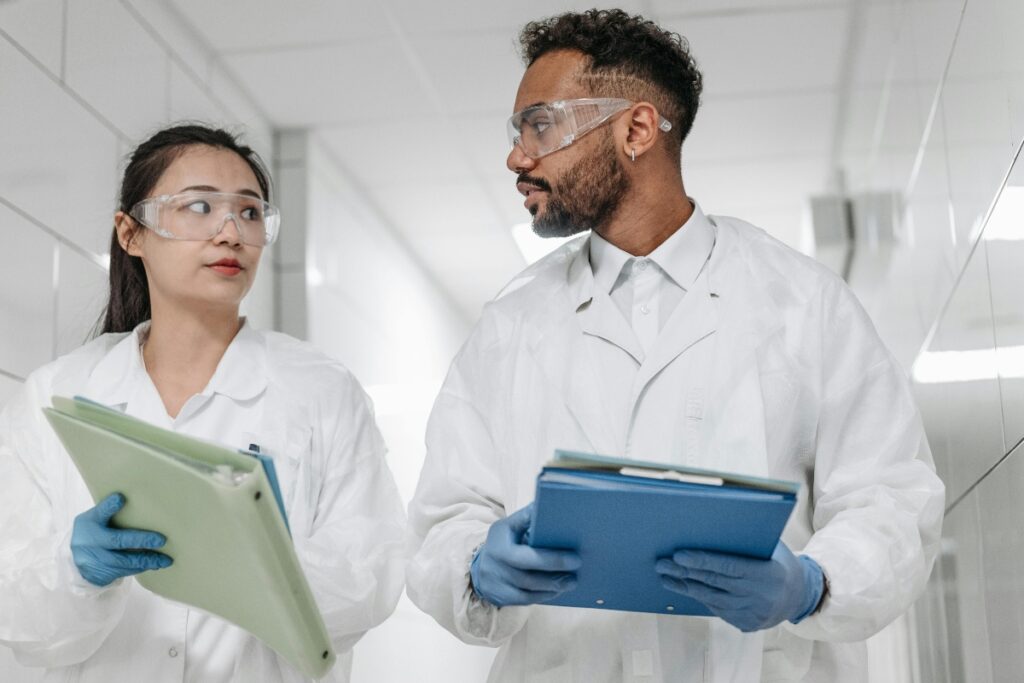 Two nursing students with protective gear and medical papers.