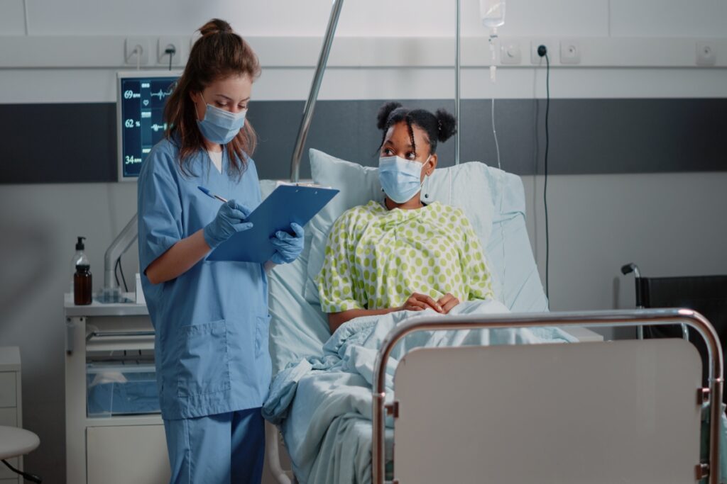 A nurse checking on a little girl in a hospital bed.